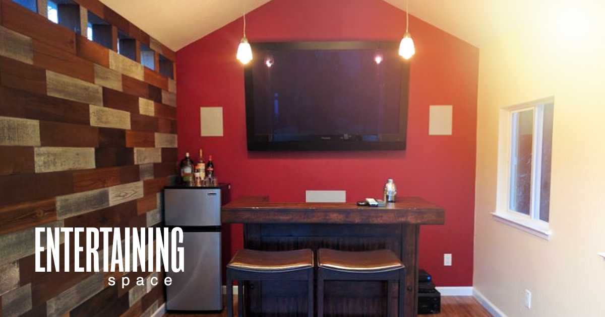 Entertaining Space Cozy room with a wooden bar, two stools, a wall-mounted TV, mini fridge, and decorative wood paneling. Text reads "Entertaining Space."