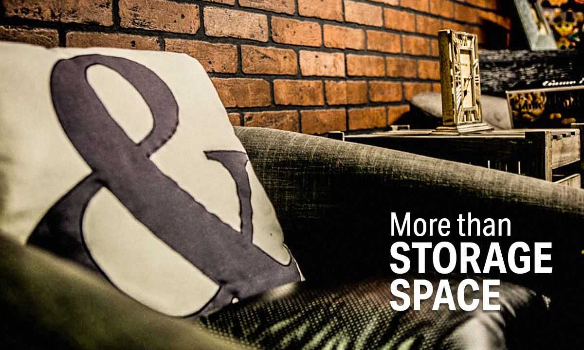 Cozy interior with a pillow featuring an ampersand, a brick wall, and text reading "More than STORAGE SPACE" in bold white letters.