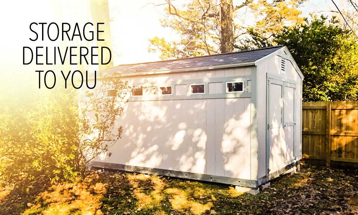 A white storage shed with small windows is placed in a sunlit backyard, surrounded by trees and a wooden fence. Text reads "Storage Delivered to You."