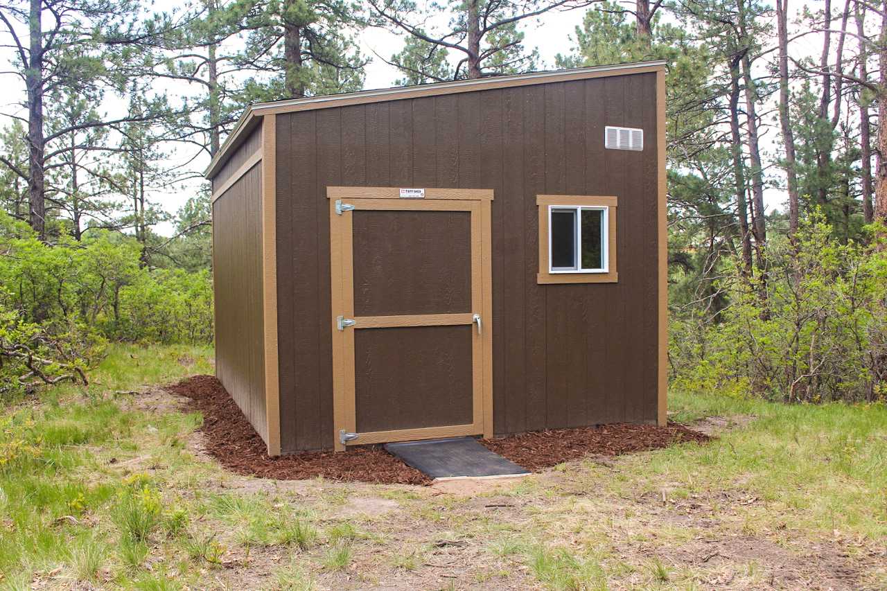 TR800 shed with a sloped roof, single door, and window, surrounded by trees and grass.