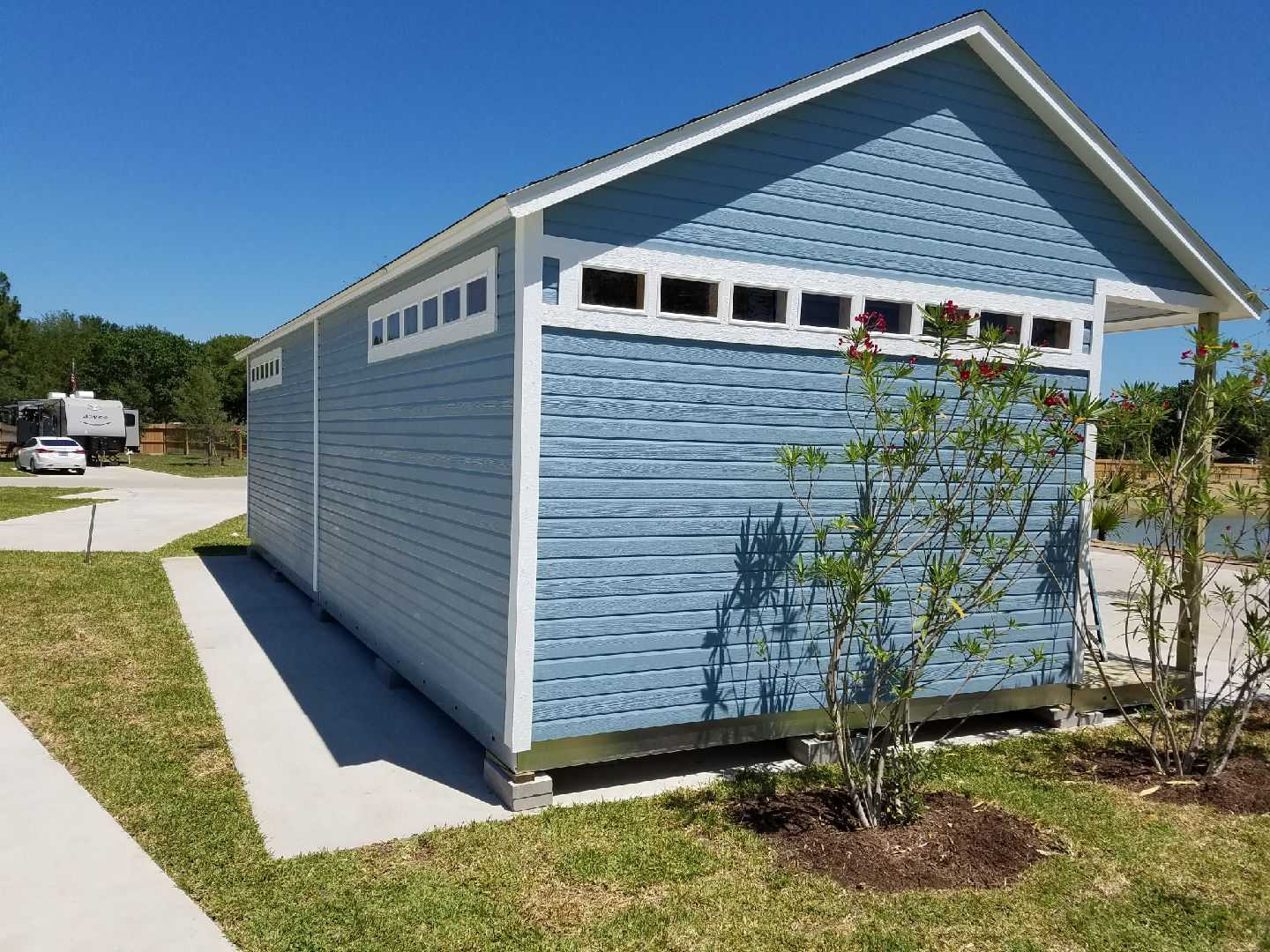 TR800 shed back view with white trim and small windows, surrounded by grass and a flowering plant