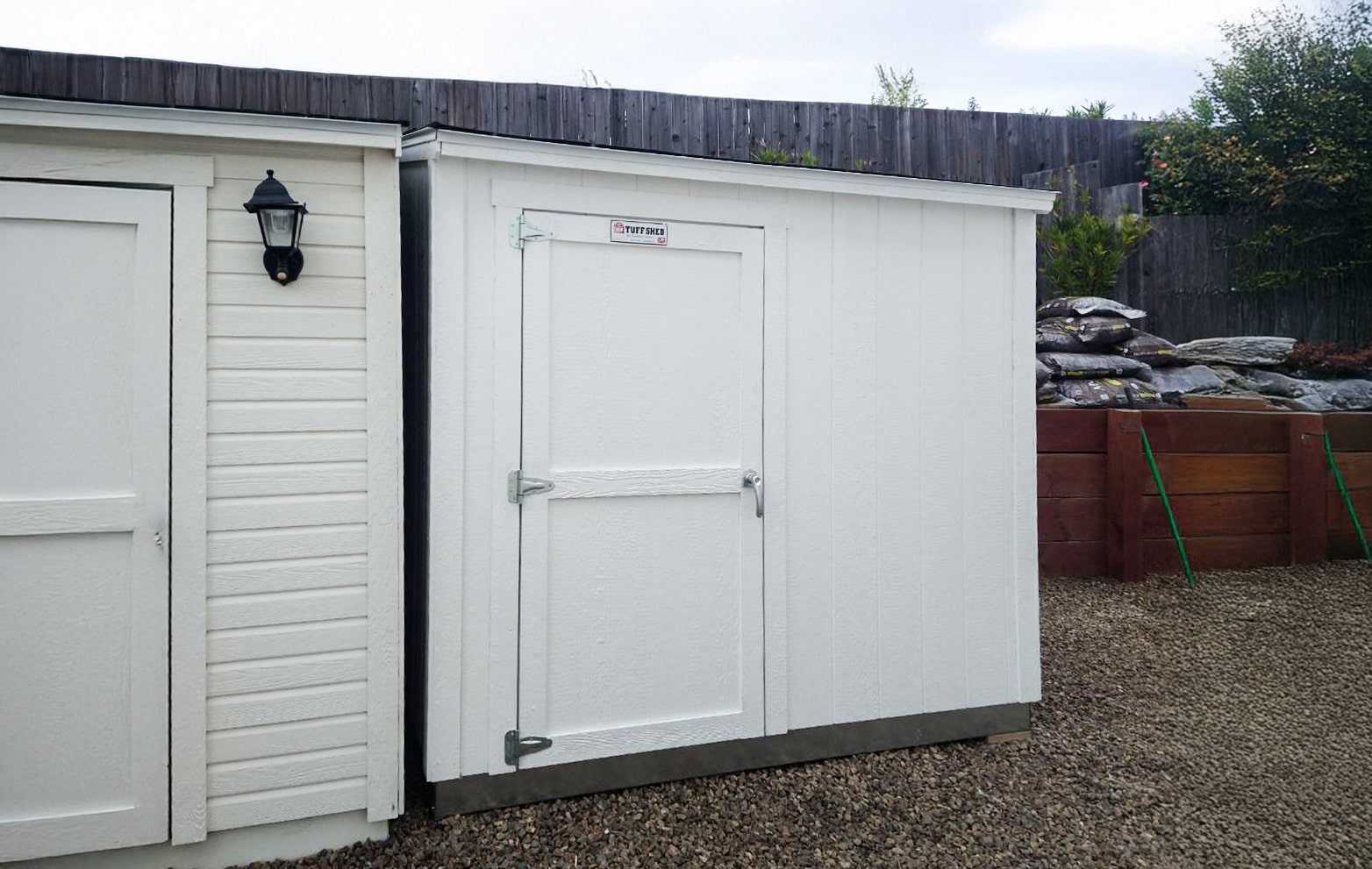 A white small lean-to shed next to another white lean-to shed with horizontal siding