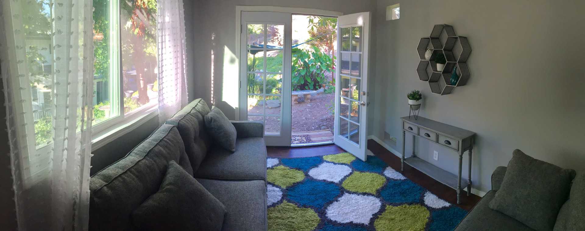 A cozy TR800 with a gray sofa, colorful rug, and open French doors leading to a garden