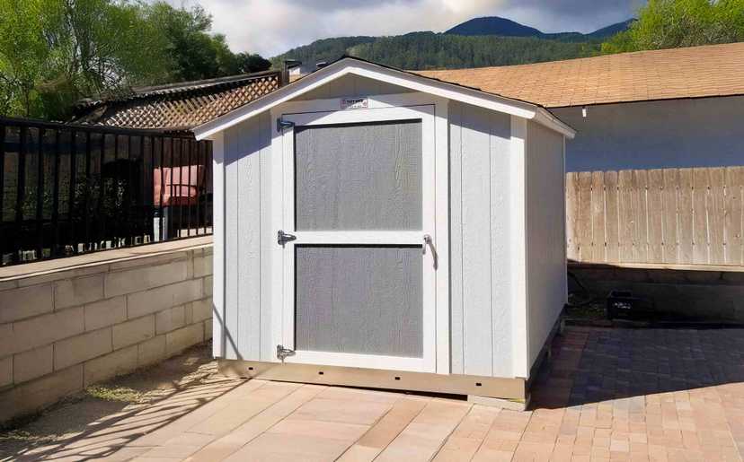 light gray ranch style shed with dark gray color door and white trim