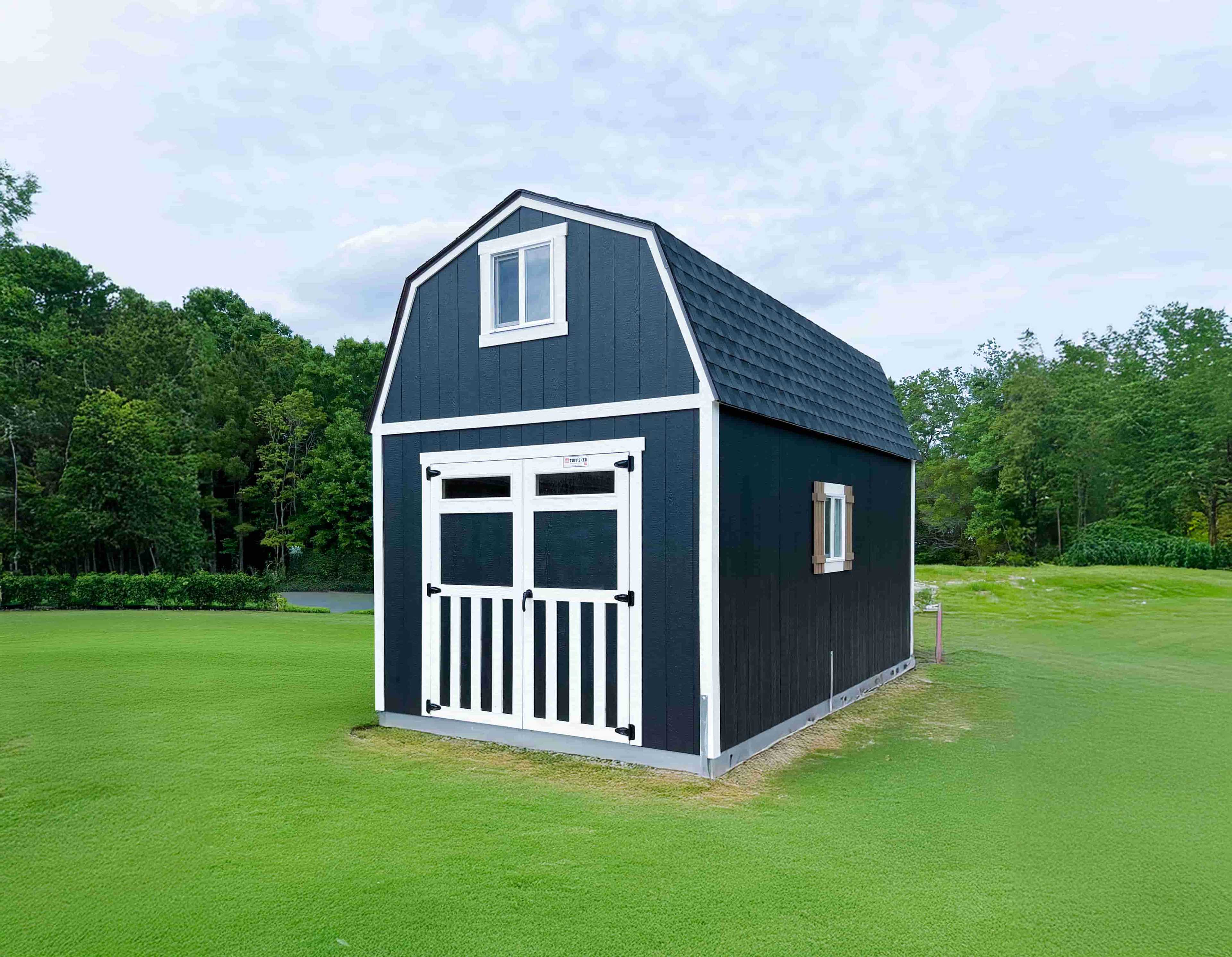 A tall black barn shed with double doors, black hardware with white trim standing a a perfect green lawn