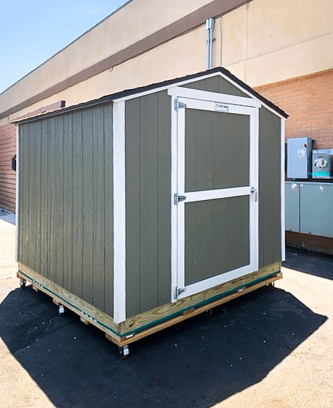 Green KR600 storage shed with white trim on a wooden platform