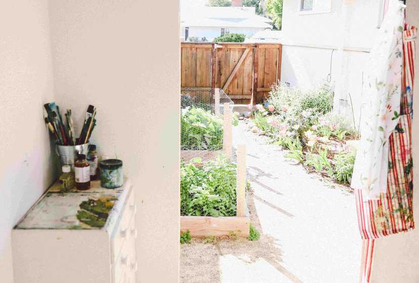 a vire to the garden from an open door of the studio, with palette and brushes set on one side table by the door