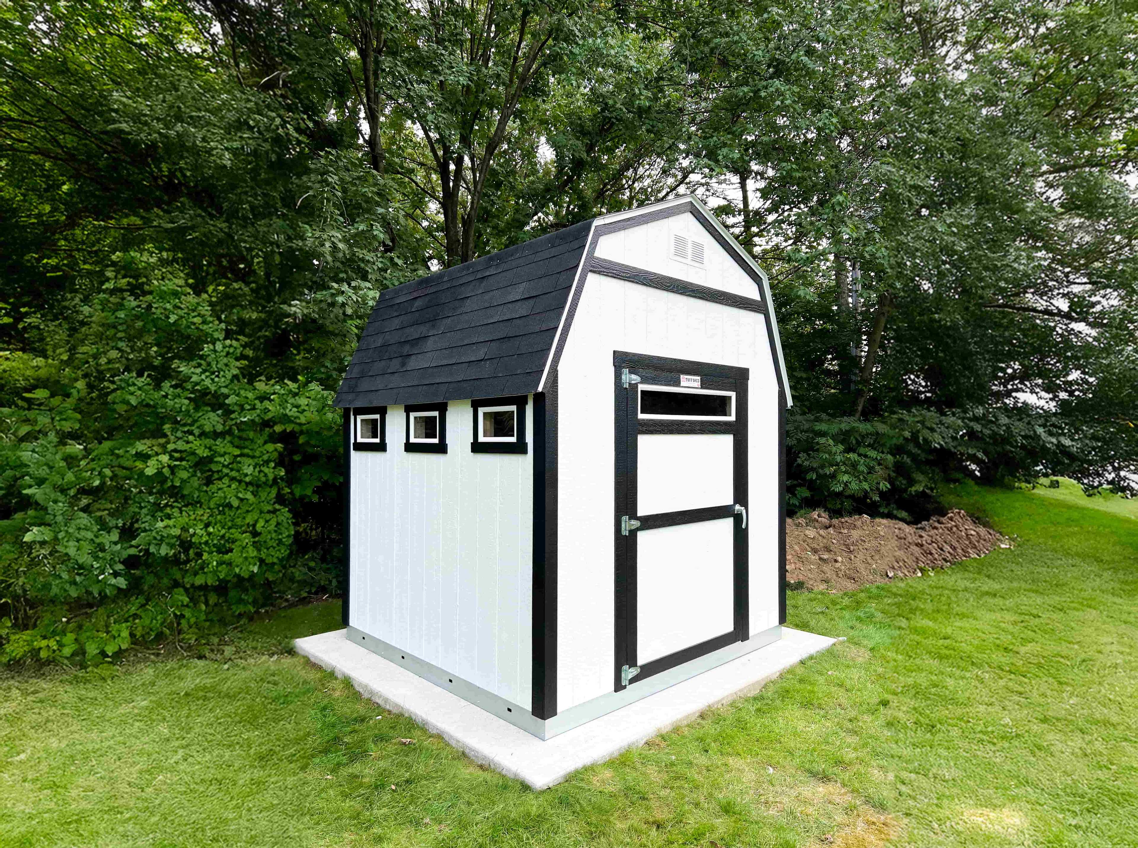 TB600 white shed with black trim, three windows, and a door, set on a concrete slab