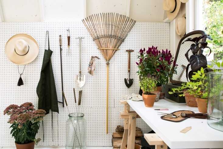 Organized interior of Michelle's potting shed. Interior of the TB600 shed with tools on a pegboard, potted plants on a table, and hats hanging on the wall.