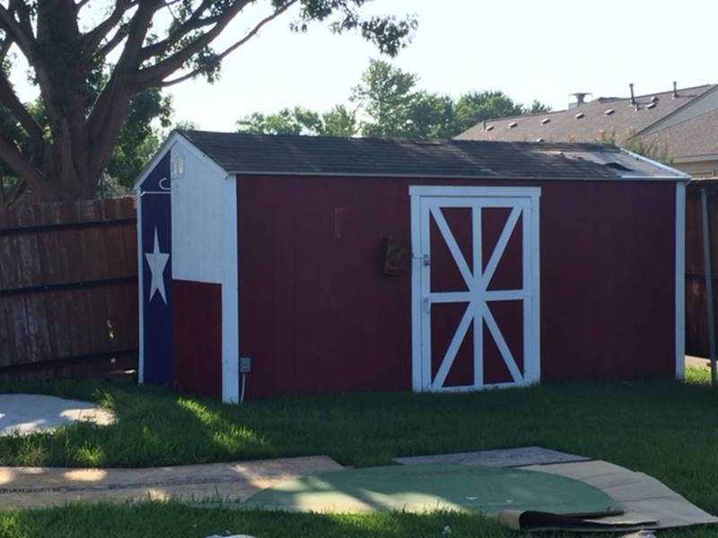 Michael's Tuff Shed building before the tornado A small red shed with a white door in a grassy backyard with a wooden fence and trees