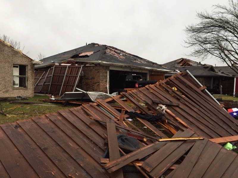 A photo of some of the destruction in Michael's neighborhood Damaged houses with roofs torn off and debris scattered after a storm