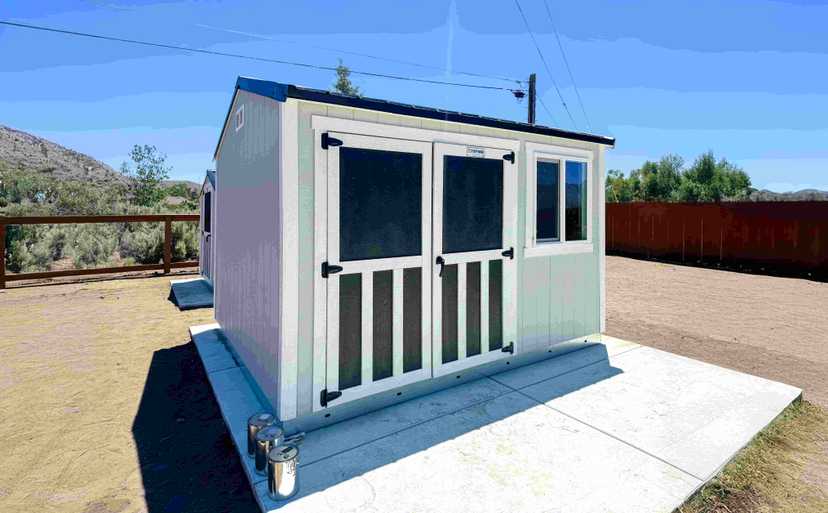 blue ranch style shed with double black doors and white trim